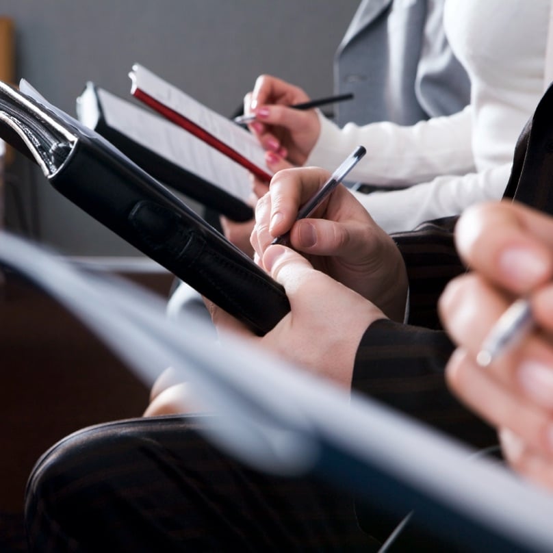 Attendees take notes during a business seminar.