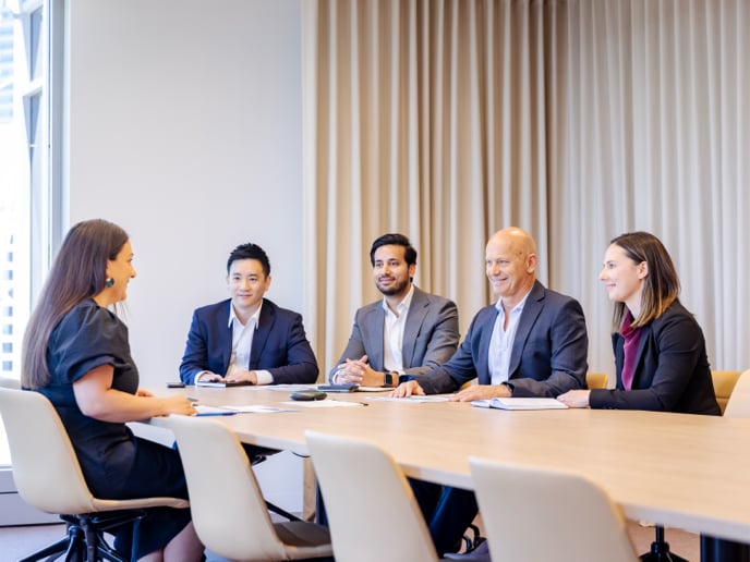 Group of 5 teammates gathering around a table for a meeting.
