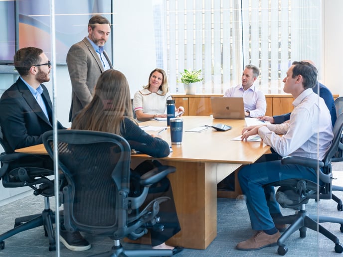 Large group of teammates sitting around a conference table in a meeting room.