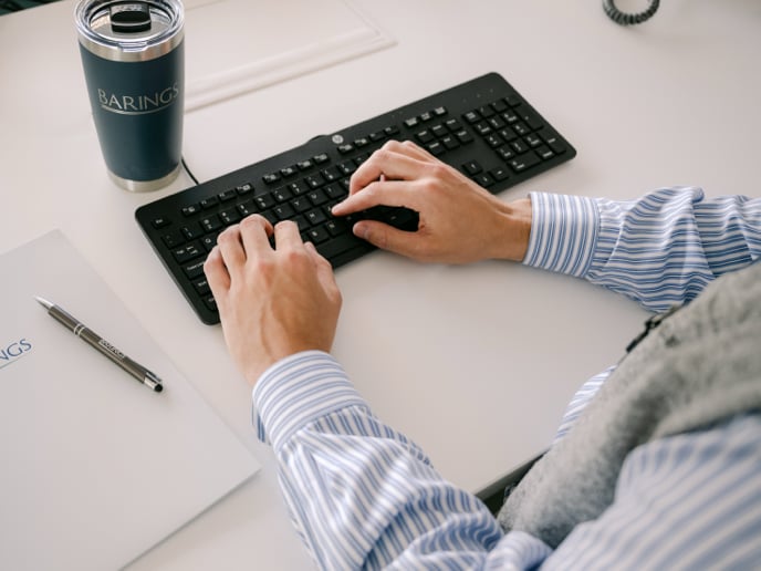 Person typing on a keyboard at their desk.