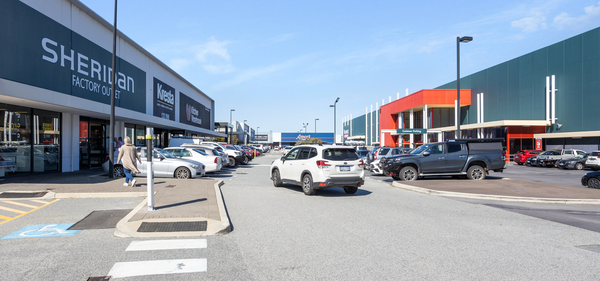 A shopping center with a parking lot with cars in front of it.