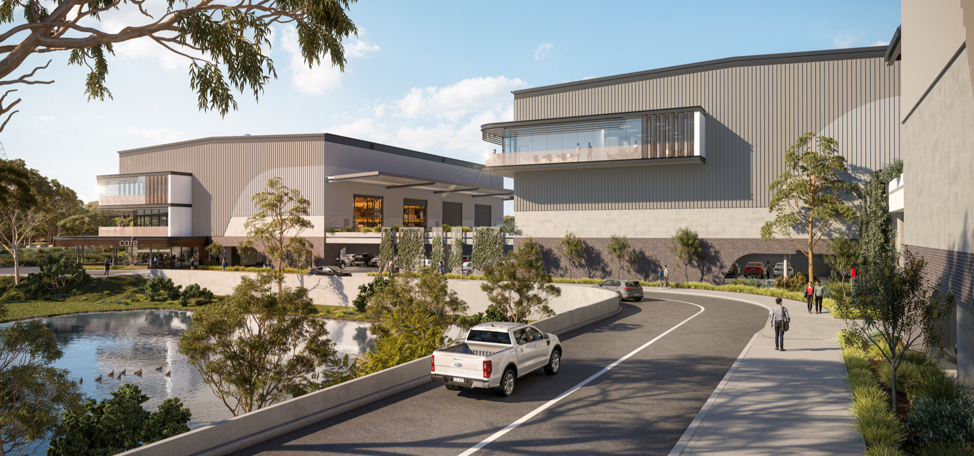 A car driving on a road next to an industrial building.