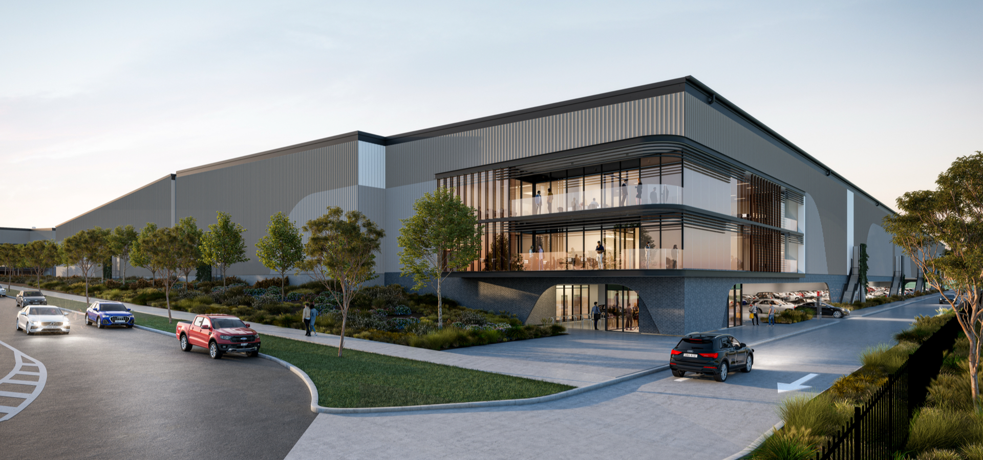An industrial building with trees and cars parked in front of it.