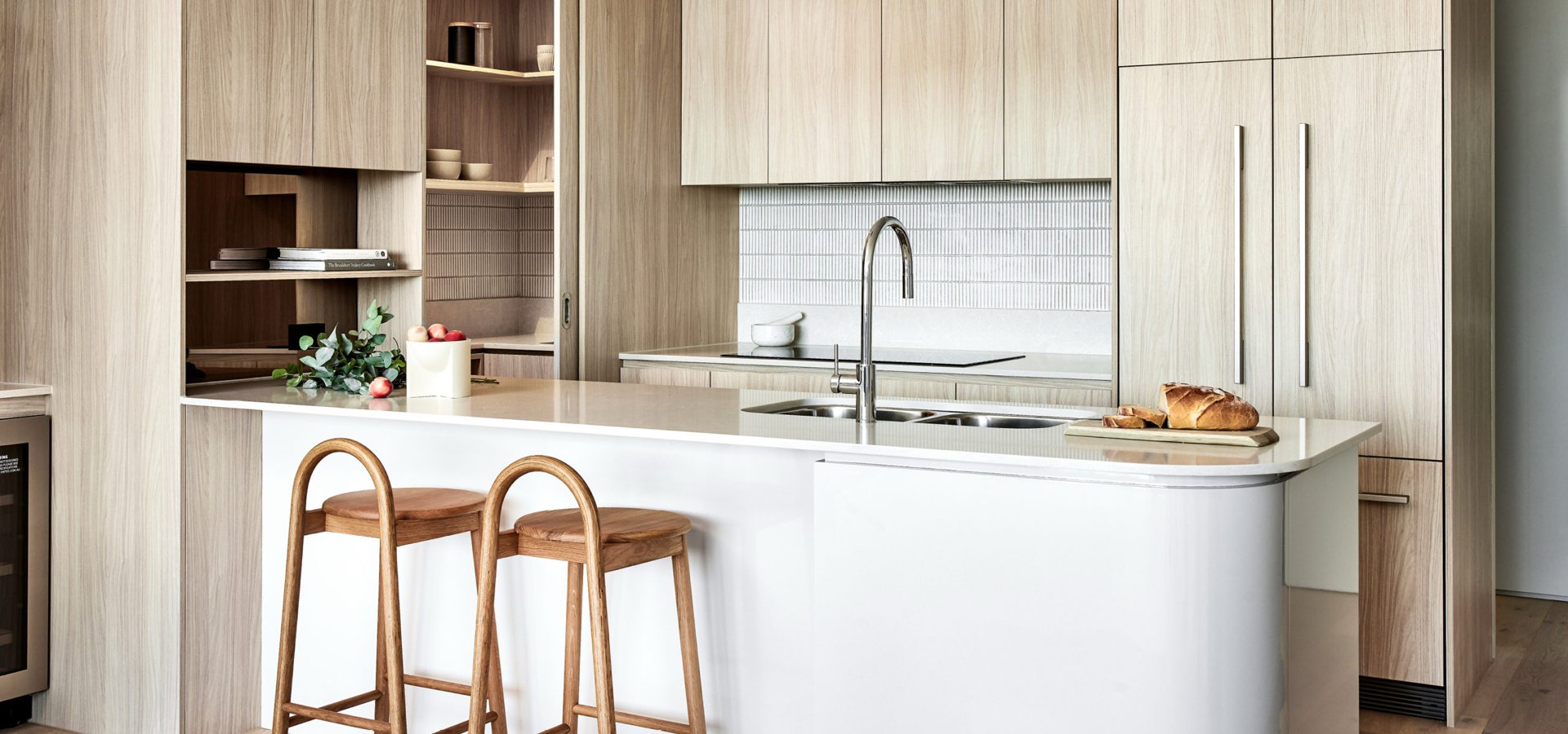 A kitchen with a sink and stools.