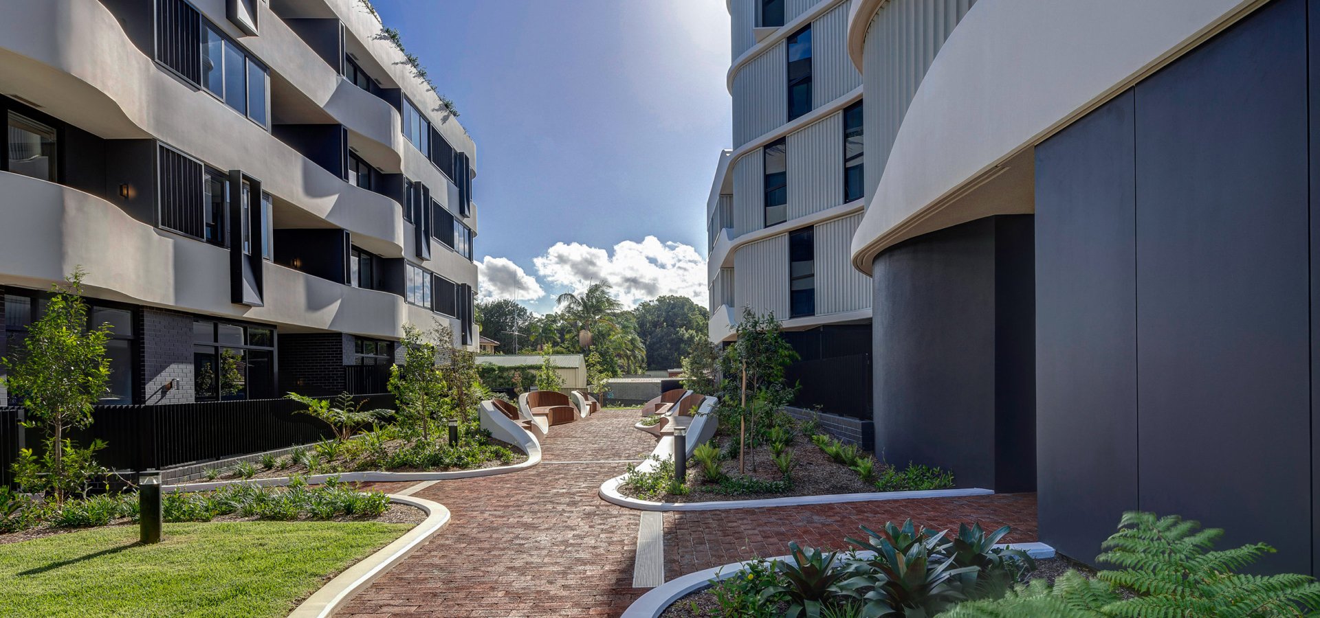 A walkway between buildings with plants and trees.