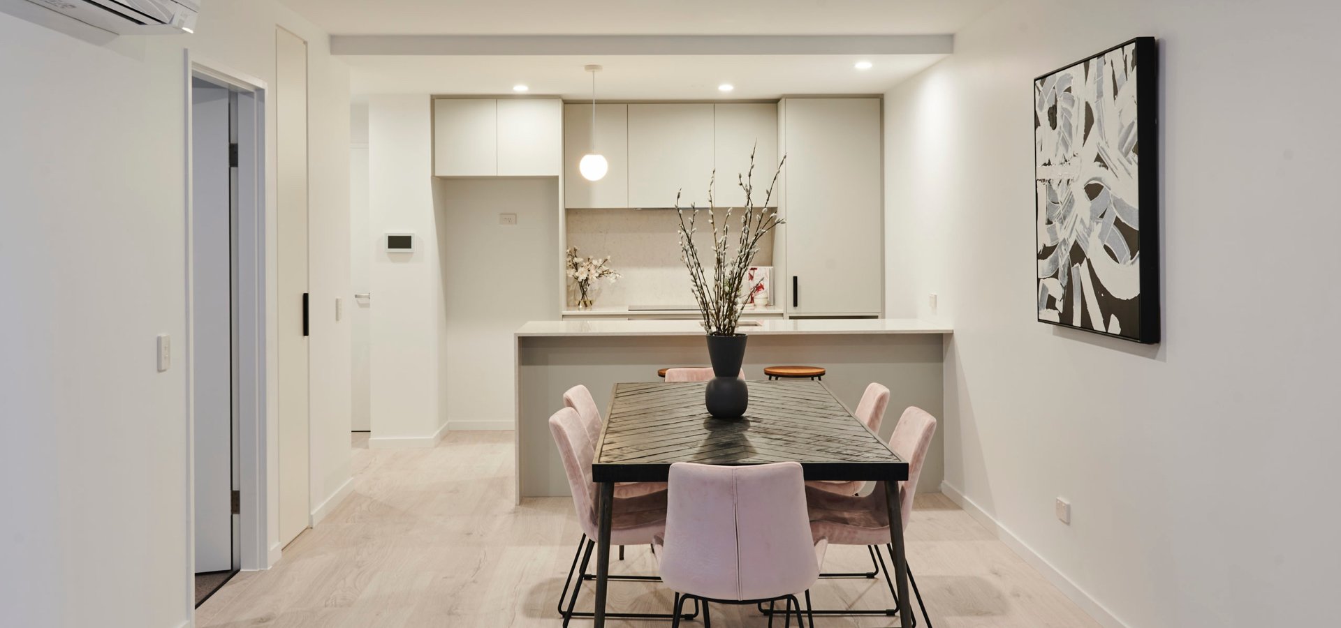 A dining table with chairs in front of a kitchen.