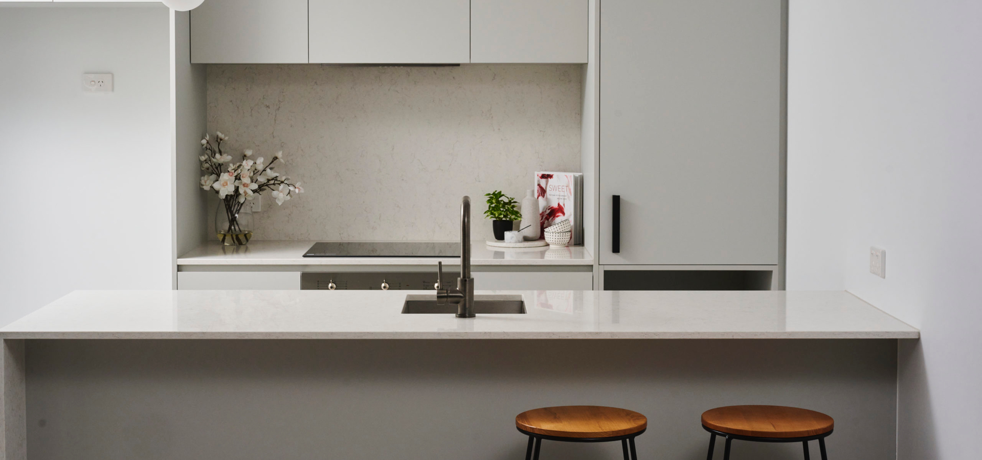 A kitchen with a sink and stools.