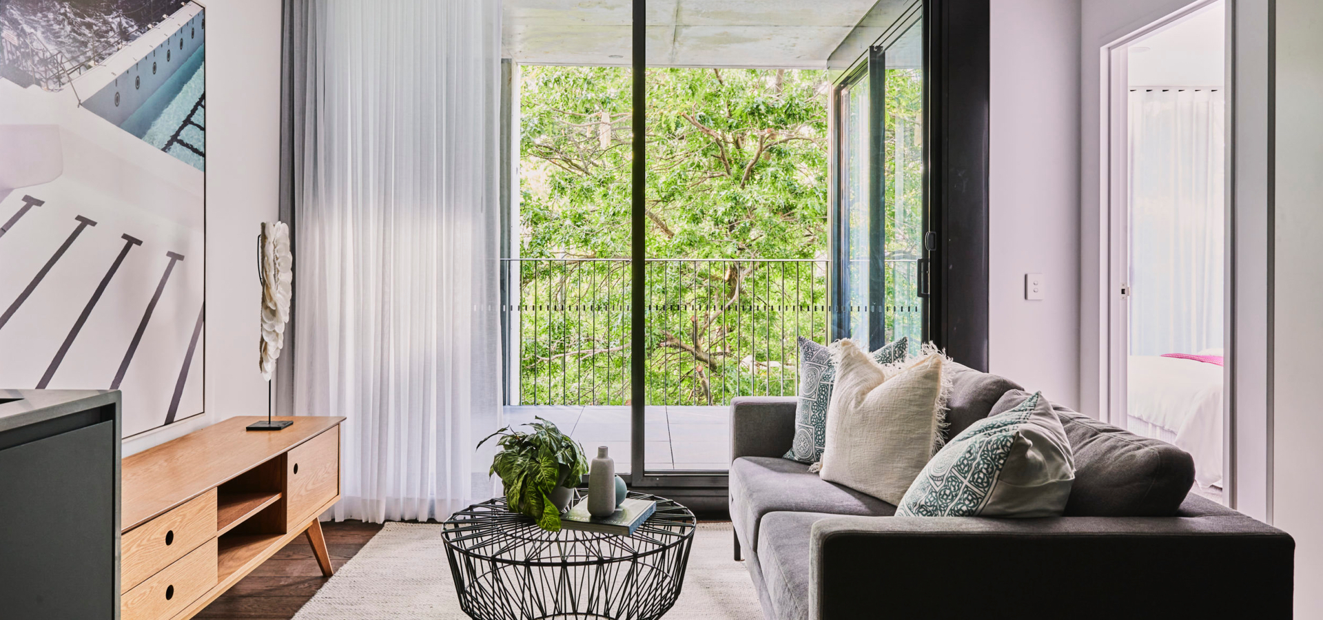 A living room with a couch and a coffee table with an outdoor deck. 