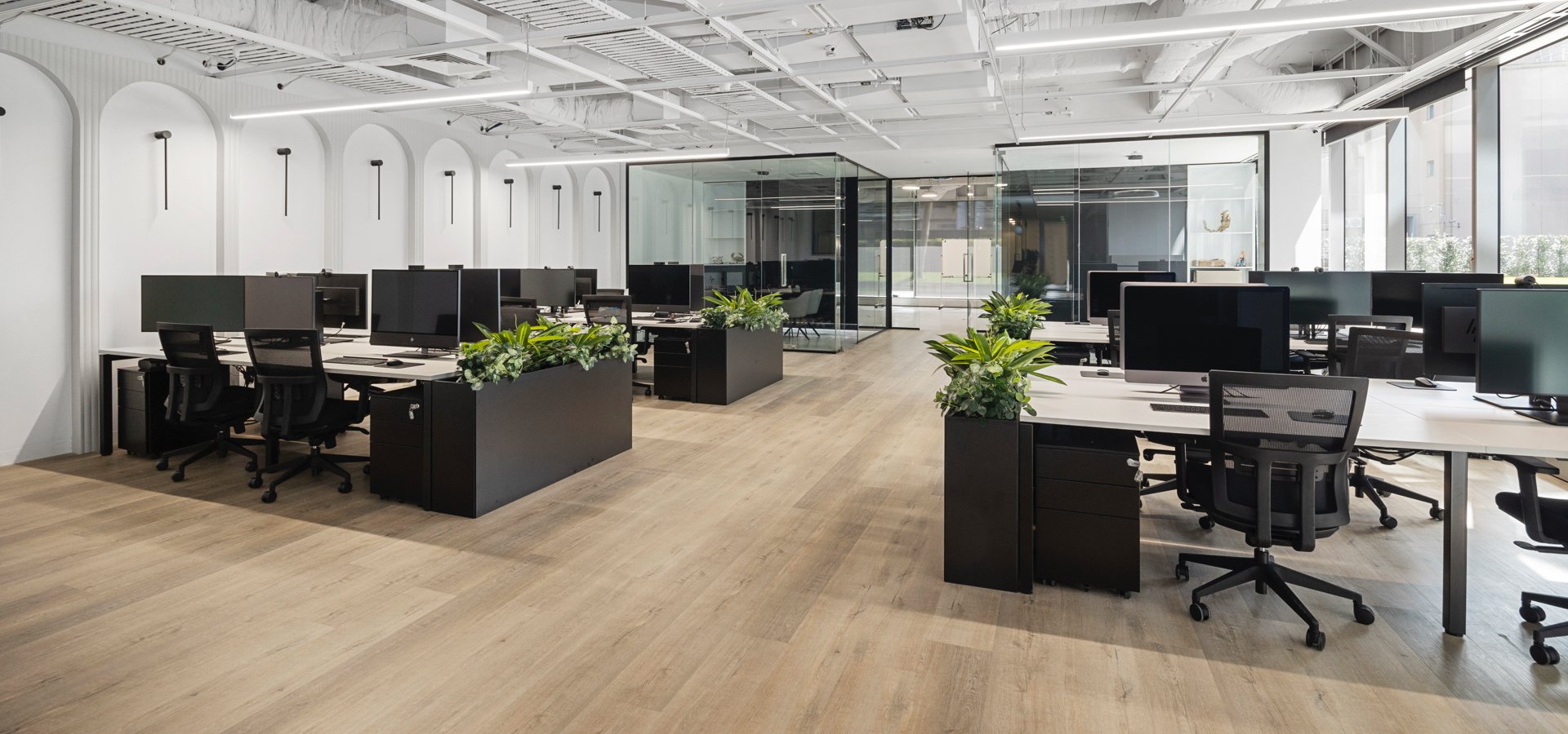 An office space with black desks and plants.