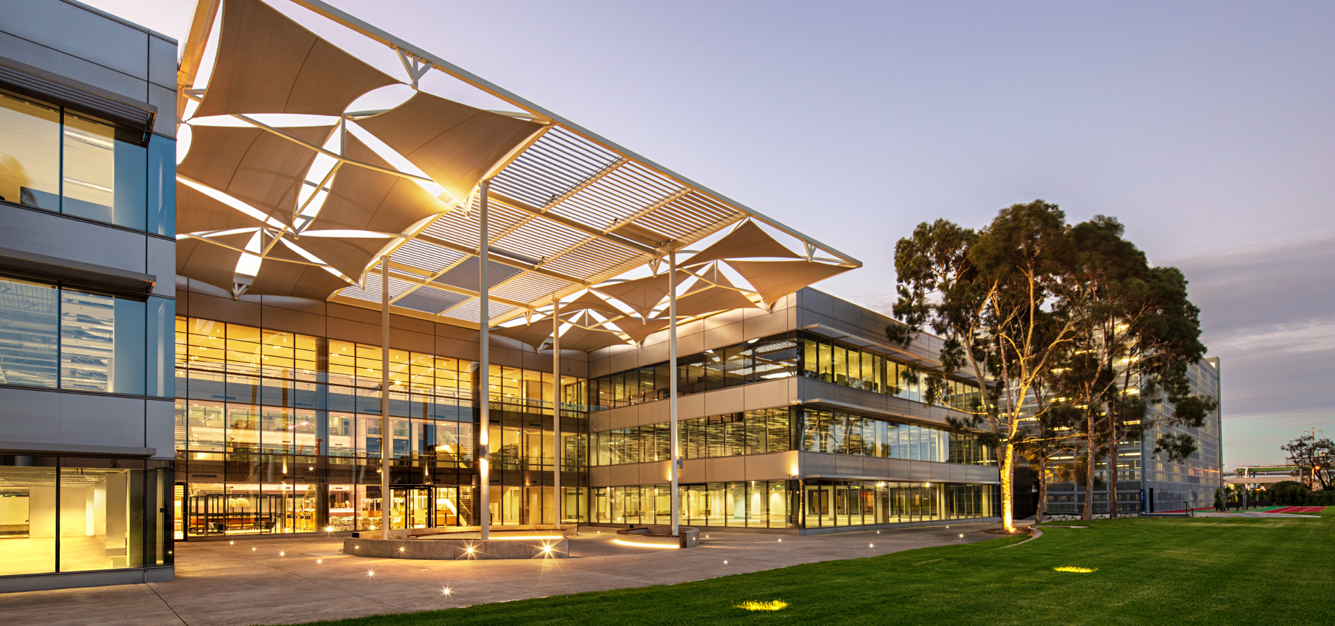 An office building at night with green grass. 