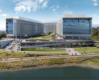 A large, grey, glass office building with green space diving the building and an angular walkway leading to a greenway and river.