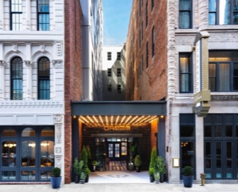 Front view of a white, black, and red, modern, brick hotel with the name “Dream” above the front door.