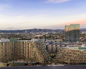 A large, green mixed-use building with angular sides in front of a large mountain range. 