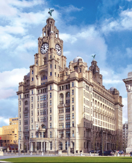 A tall, baroque, tan office building with a large clock tower in the center.  
